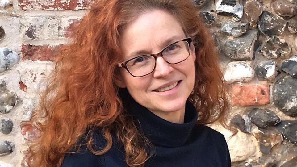 Headshot of Jo smiling in front of a brick wall